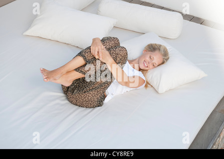 Young woman relaxing on lit dans la position du fœtus Banque D'Images