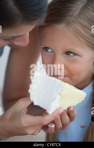 L'alimentation de la mère tranche de gâteau de petite fille Banque D'Images