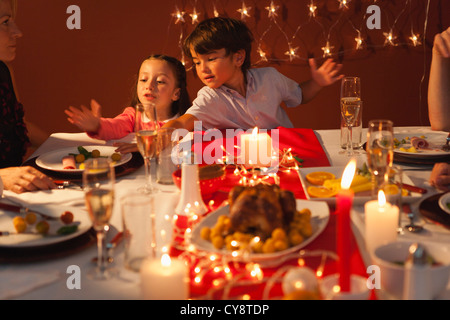 Petit garçon et petite fille jouant pendant le dîner de Noël Banque D'Images