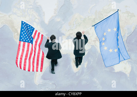Businessman walking sur le dessus de la carte du monde, portant des drapeaux de l'Union européenne et américaine Banque D'Images