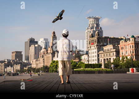 Un homme vole un cerf-volant tôt le matin sur le Bund contre les toits de Shanghai, Chine moderne Banque D'Images