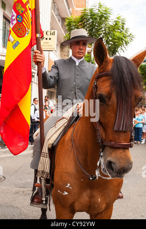 Les hommes de l'équitation dans une procession religieuse à Fuengirola. L'Espagne. Drapeau national ou religieux portant bannière. Banque D'Images