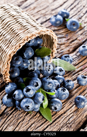 Les bleuets ont chuté à partir du panier sur une vieille table en bois. Banque D'Images