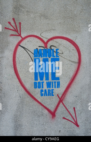Graffitti coeur et slogan "Touchez-moi mais avec soin' sur un mur à Dublin, Irlande Banque D'Images