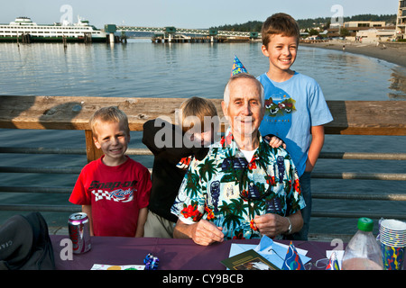 83 ans, homme, et pose avec 3 petits-fils tout en célébrant son anniversaire à l'extérieur avec les membres de la famille sur la jetée de Edmonds, Washington Banque D'Images
