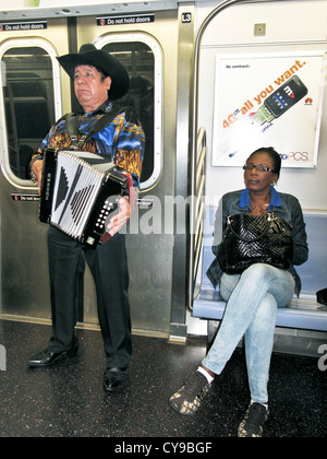 Dans l'accordéoniste mexicain chaussures pointues & sombrero, partie d'un trio, joue sur New York Subway train comme femme noire écoute passager Banque D'Images