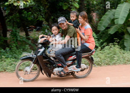 Un heureux jeune famille passent sur une moto à O'Ambel village, Sisophon, Cambodge Banque D'Images