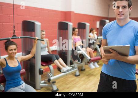 Formateur dans une salle de musculation avec les femmes Banque D'Images