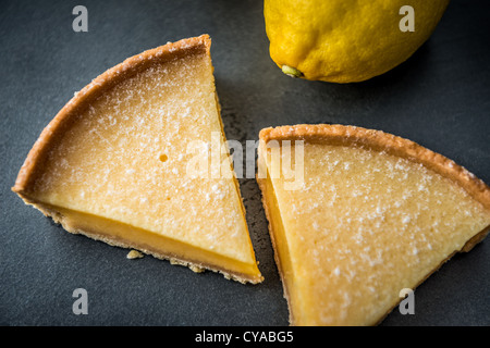 Tarte au citron dessert avec base de biscuit sur la surface de l'ardoise de citrons en arrière-plan en plongée des Banque D'Images