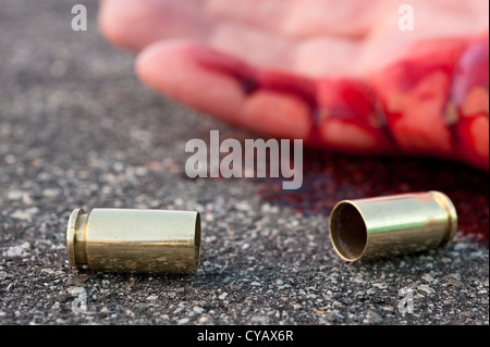 Un homme abattu dans la rue avec le boîtier cylindrique portant à côté d'une main. Banque D'Images