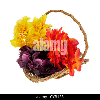 Un petit panier en osier rempli de fleurs artificielles colorées sur un fond blanc. Banque D'Images