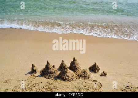 Château de sable sur une plage vide avec ocean surf doux Banque D'Images