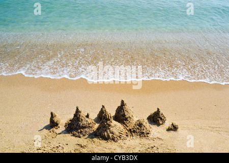 Château de sable sur une plage vide avec ocean surf doux Banque D'Images