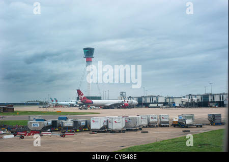 Assurance des conteneurs sur l'aéroport de Londres Heathrow, avec la tour de contrôle et les avions à l'arrière-plan Banque D'Images