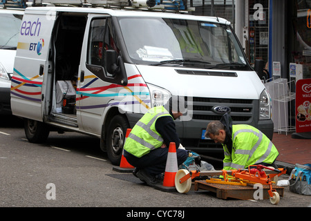 Deux ingénieurs BT Openreach photographié travaillant dans un trou dans le sol dans la rue à Brighton, East Sussex, UK. Banque D'Images