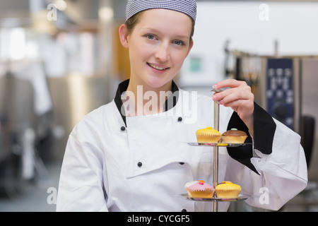 Happy chef holding tiered cake tray Banque D'Images