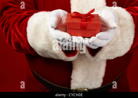 Photo de Père Noël les mains gantées tenant coffret rouge Banque D'Images