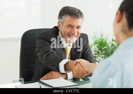 Man shaking a woman's hand dans un bureau Banque D'Images