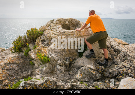 Un homme se penche sur le tronc d'un arbre fossilisé dans la forêt fossile de Lulworth Cove, près de dans le Dorset UK Banque D'Images
