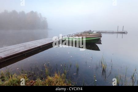 Petite jetée en bois avec des bateaux sur le lac dans le froid matin brumeux Banque D'Images