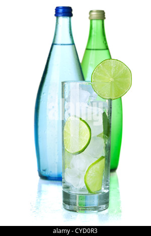 Verre d'eau avec de la chaux et de glace, deux bouteilles avec de l'eau minérale. Isolé sur fond blanc. Banque D'Images