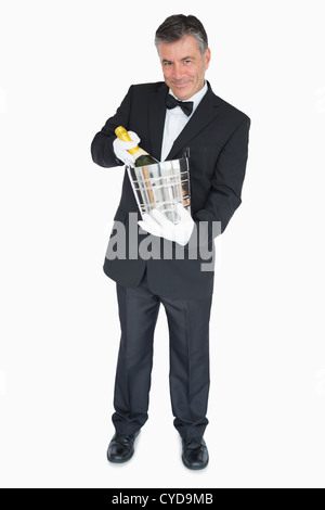 Waiter offering bouteille de champagne dans le refroidisseur Banque D'Images