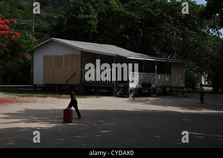 Deux jeunes garçons jouent au cricket Indien de l'Ouest, l'ouatine bowiling, à l'ombre des arbres, Paradise Beach car-park, Carriacou, West Indies Banque D'Images