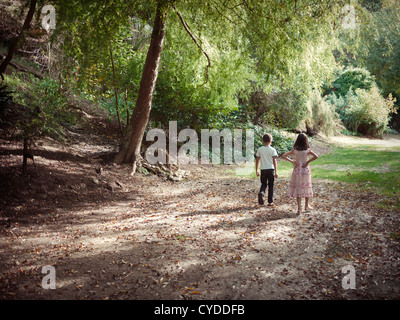 Garçon et fille marcher le long chemin forestiers dans le soleil l'après-midi Banque D'Images