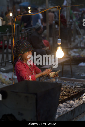 Jeune Jeune Fille ouïghoure Préparation brochettes dans le marché de nuit, Hotan, la région autonome ouïghoure du Xinjiang, Chine Banque D'Images