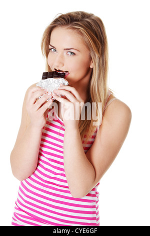 Happy teen caucasian girl biting une barre de chocolat. Banque D'Images