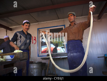 Uyghur Man Making Fresh Laghman nouilles dans Kashgar Marché des animaux, la région autonome ouïghoure du Xinjiang, Chine Banque D'Images