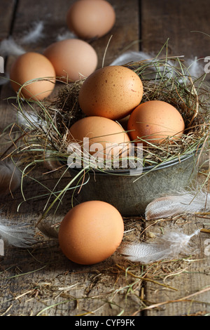 Brown frais oeufs dans le vieux récipient d'étain sur fond de bois Banque D'Images