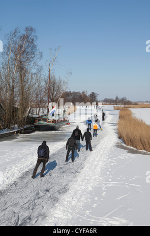 Les Pays-Bas, Jisp, hiver. Les gens patinoire sur polder canal devant ferme et péniche. Banque D'Images
