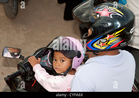 Père avec ma petite fille sur une moto portant des casques de protection, Phnom Penh, Cambodge Banque D'Images