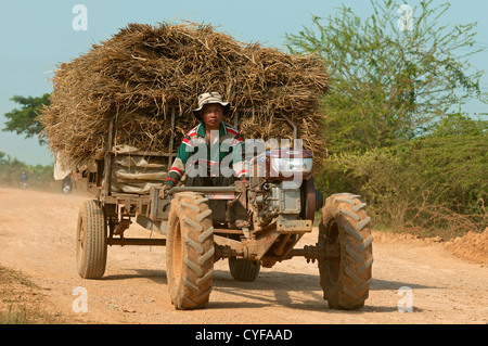 Tracteur à deux roues transportant la paille de riz en vrac on rural Road dans la zone de production de riz de Battambang, Cambodge Banque D'Images