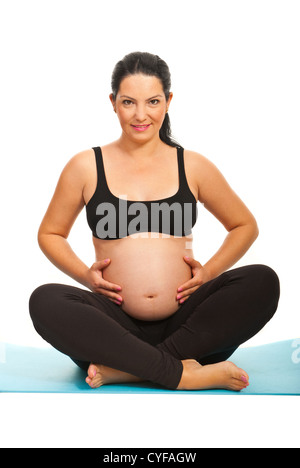 Happy pregnant woman standing on fitness tapis bleu et de toucher son ventre contre fond blanc Banque D'Images