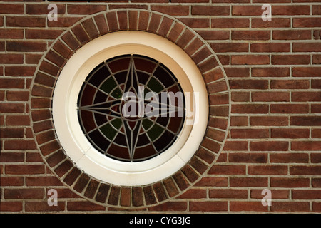 Fenêtre en verre au plomb rond situé dans mur de brique rouge Banque D'Images