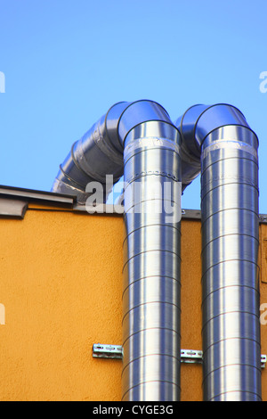 Deux gaines de ventilation de ramper sur un mur jaune Banque D'Images