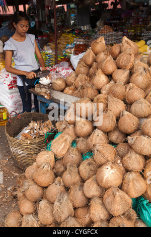 Femme vendant et couper des noix de coco au marché de Pakse, Laos Banque D'Images