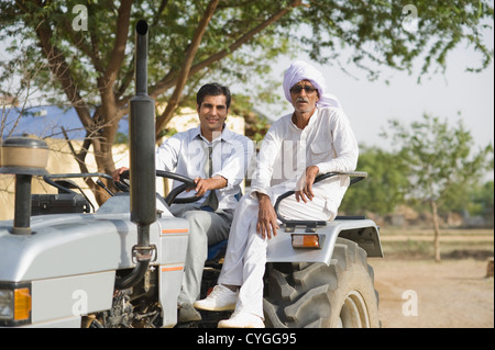 Farmer assis sur un tracteur avec son fils Banque D'Images