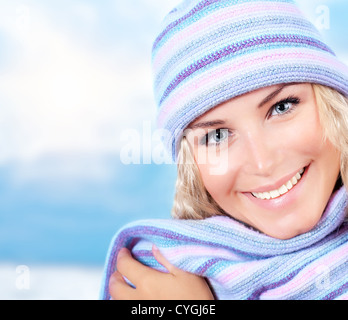 Photo de cute blonde girl wearing blue bonnet et écharpe chaude, closeup portrait de belle femme vêtue de chapeau en laine élégant Banque D'Images