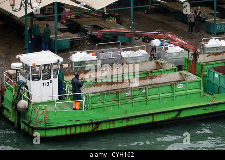 La collecte de déchets sur le site de l'ancienne criée à Venise - Poubelles de déchets sont recueillies et avec l'embout dans un chaland vert Banque D'Images