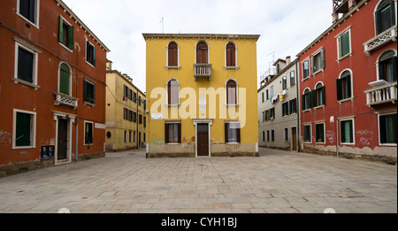 Maisons peintes en ocre rouge et jaune à l'extérieur de l'église catholique de Venise Gesuiti Banque D'Images