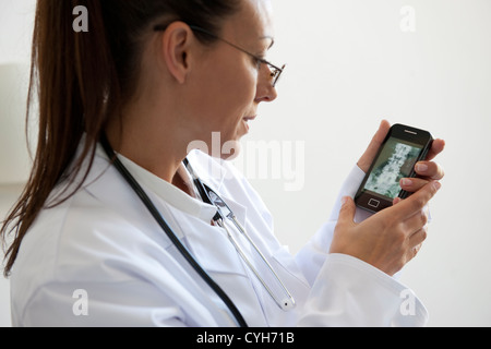 Femme médecin à la recherche de x-ray sur smartphone Banque D'Images