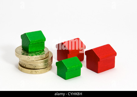 La pile de pièces livre rouge et vert avec des maisons en bois isolé sur fond blanc Banque D'Images