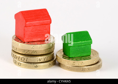 Deux piles de la pièces livre rouge et vert avec des maisons en bois. La plus grande pile a la maison plus grande Banque D'Images