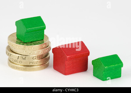 La pile de pièces livre rouge et vert avec des maisons en bois isolé sur fond blanc Banque D'Images