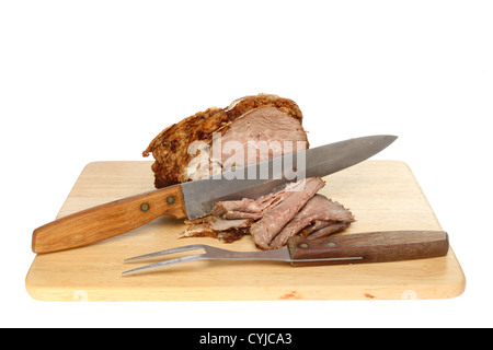 Rôti de boeuf avec un couteau et fourchette sur une planche en bois isolés contre white Banque D'Images