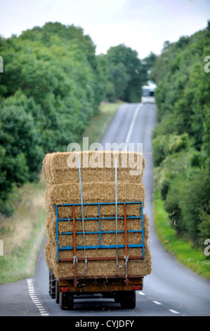 Un tracteur tractant une remorque de foin sur une route dans le Gloucestershire UK Banque D'Images