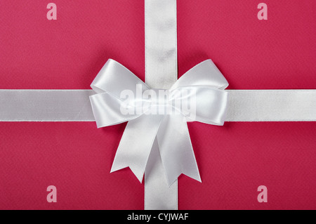 Ruban blanc avec noeud sur un fond rose Banque D'Images